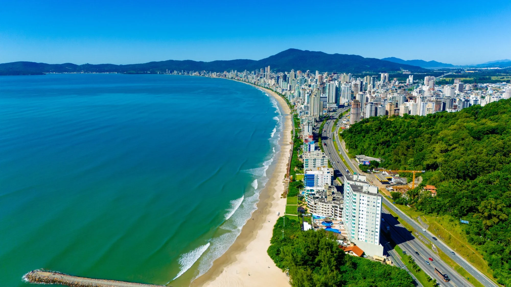 Vista aérea da Meia Praia em Itapema SC com o mar verde e a orla urbanizada