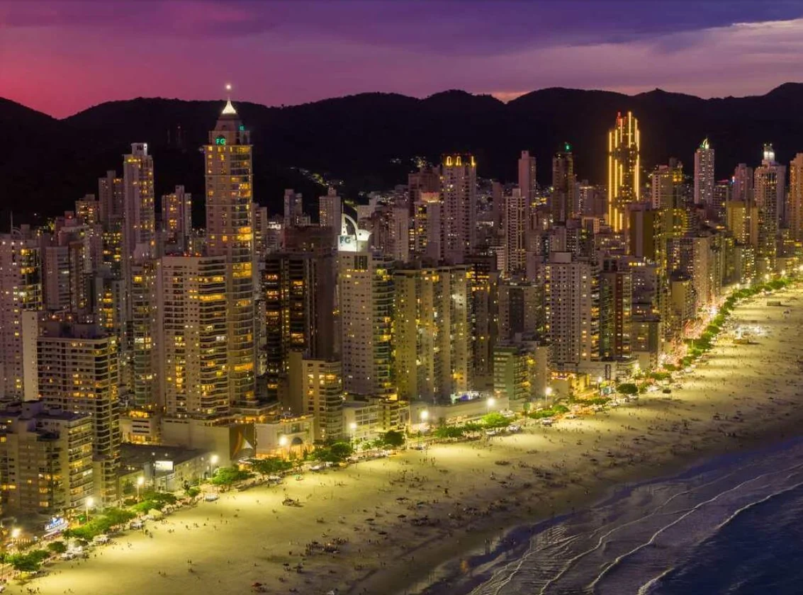 Vida noturna Balneário Camboriú Praia Central iluminada arranha-céus à noite movimento turistas